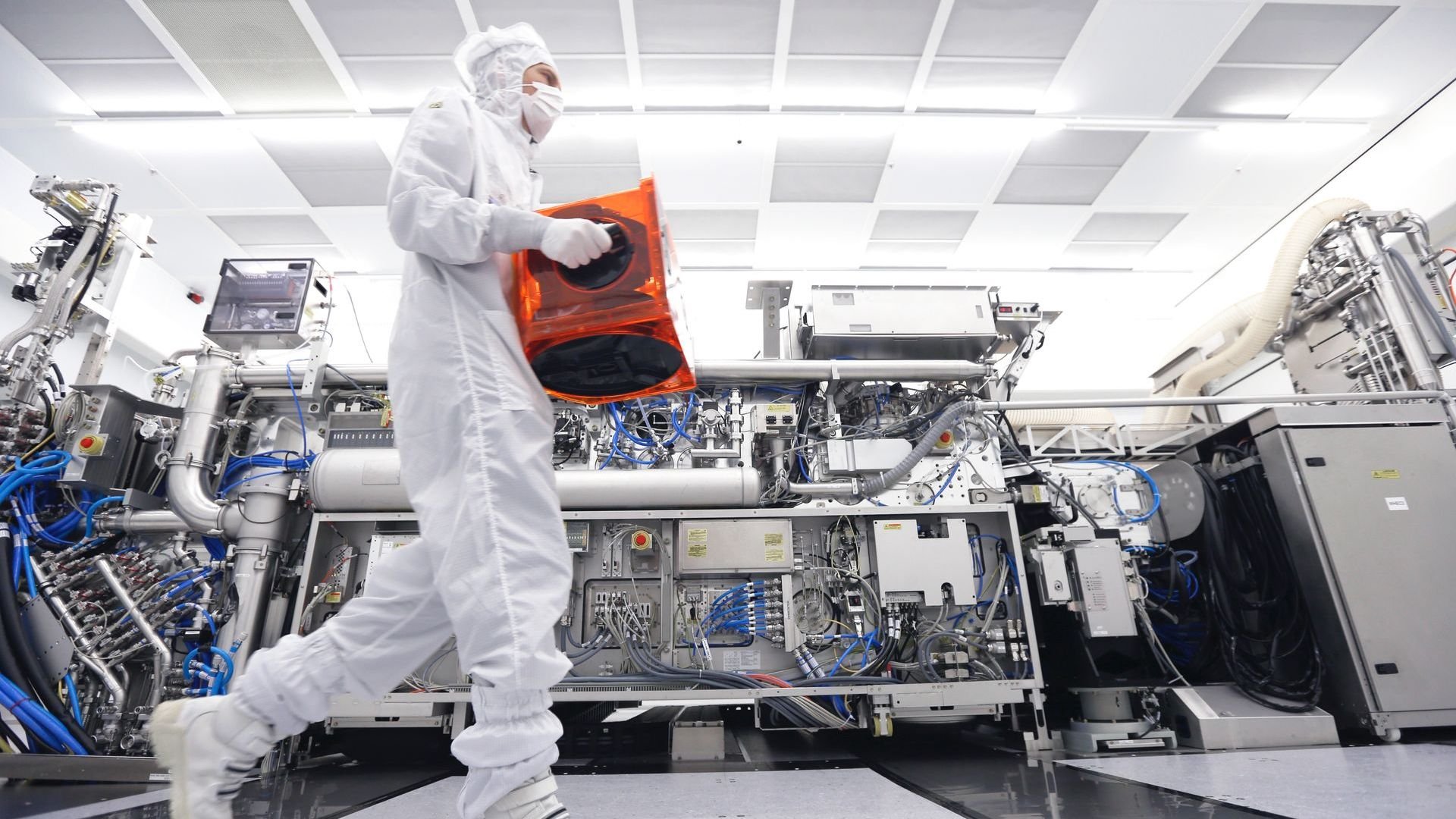 An ASML cleanroom technician carries a FOUP containing wafers. An ASML cleanroom technician carries a FOUP containing wafers.
