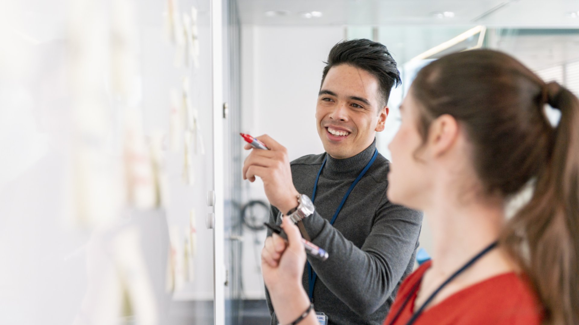 Two ASML colleagues work together on a whiteboard.