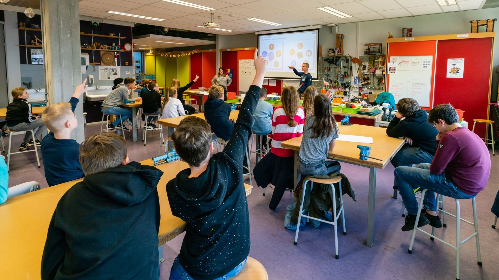 Children in a STEM classroom raise their hands in response to a teacher. Children in a STEM classroom raise their hands in response to a teacher.