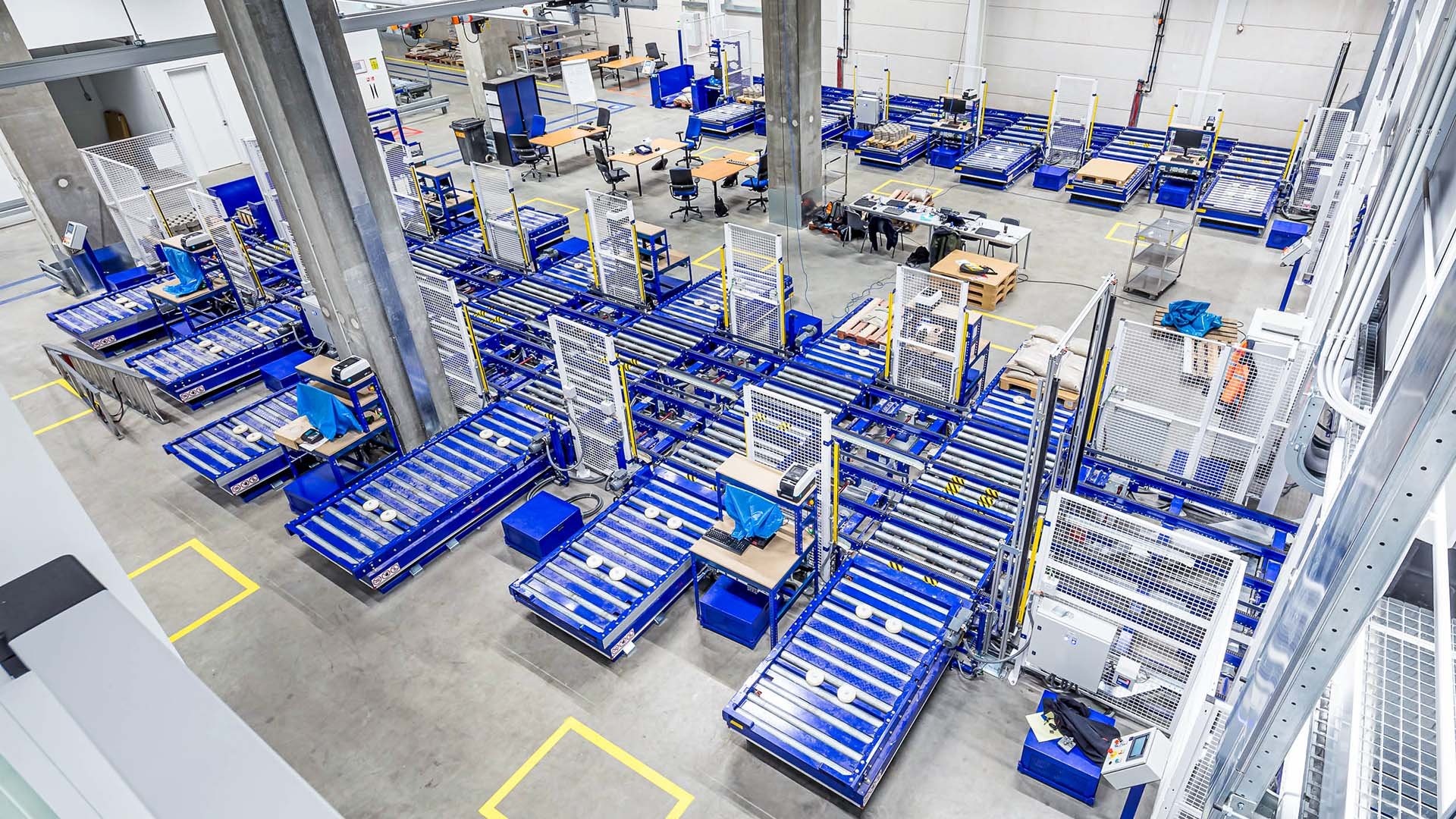 Overhead view of ASML's warehouse logistics, showcasing rows of blue storage racks with equipment and components. Overhead view of ASML's warehouse logistics, showcasing rows of blue storage racks with equipment and components.