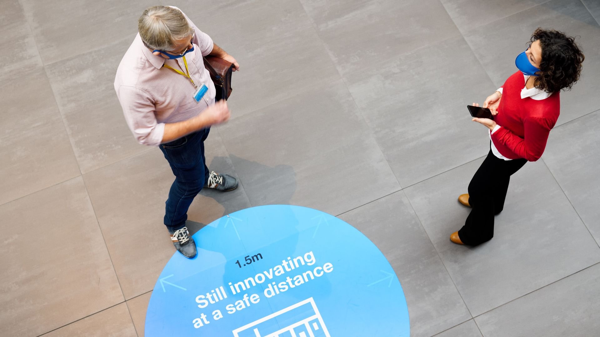 man and woman talking standing over sign for COVID-19 social distancing 