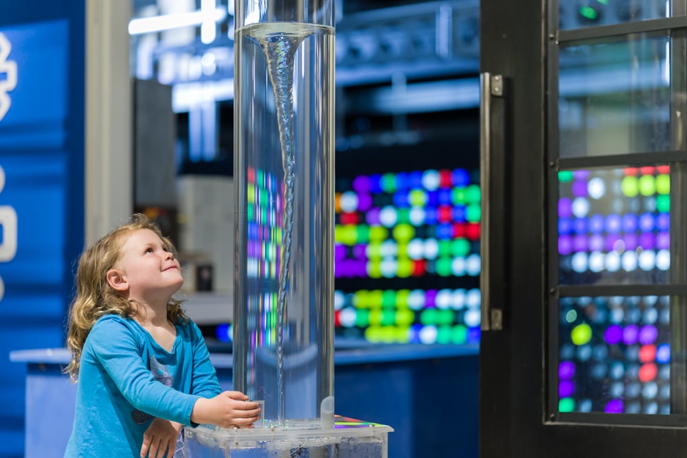 young girl staring up at water vortex in clear tube young girl staring up at water vortex in clear tube
