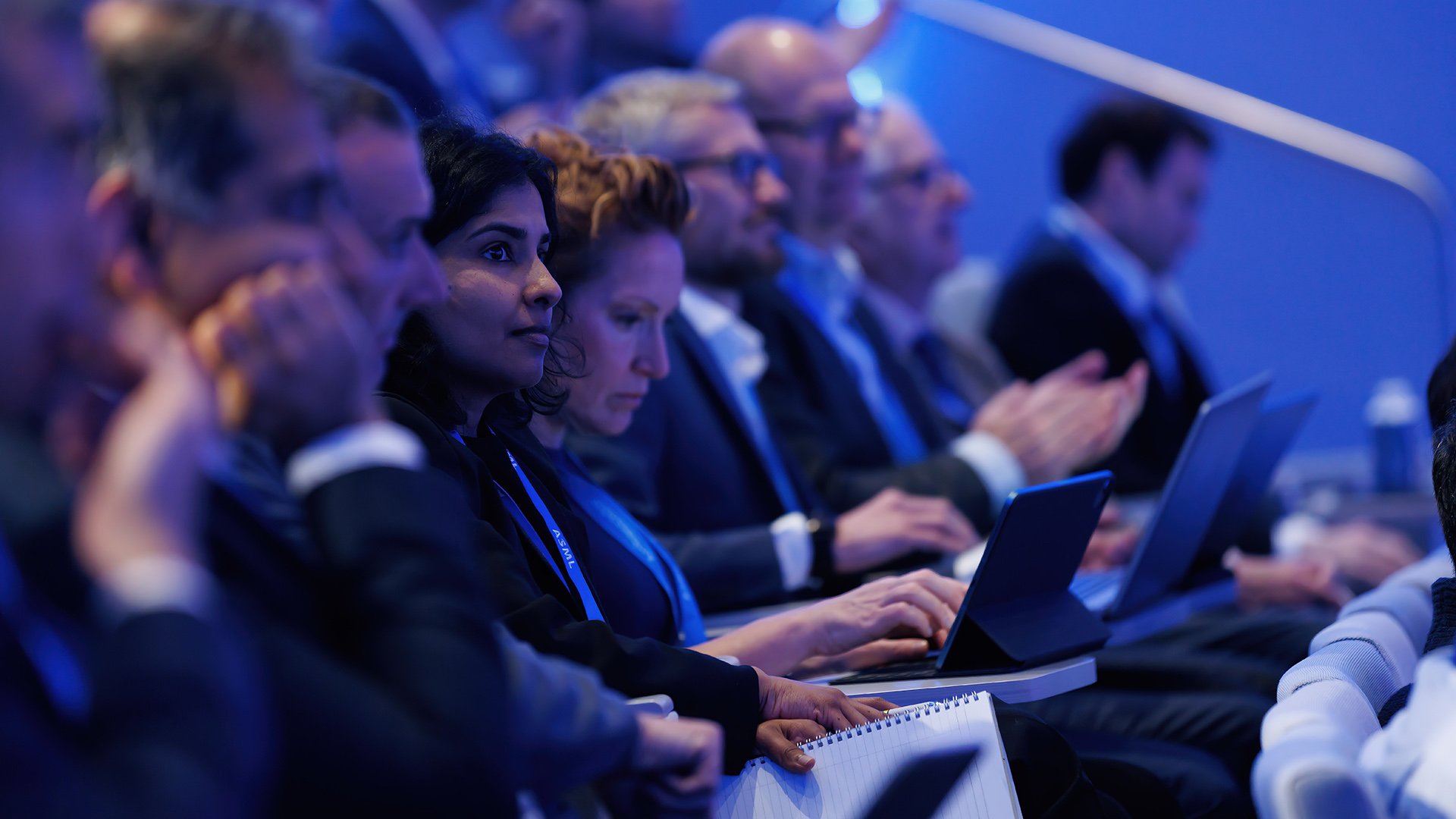 Attendees at Investor Day focusing intently on presentations, with some using laptops, captured in an ASML auditorium. Attendees at Investor Day focusing intently on presentations, with some using laptops, captured in an ASML auditorium.