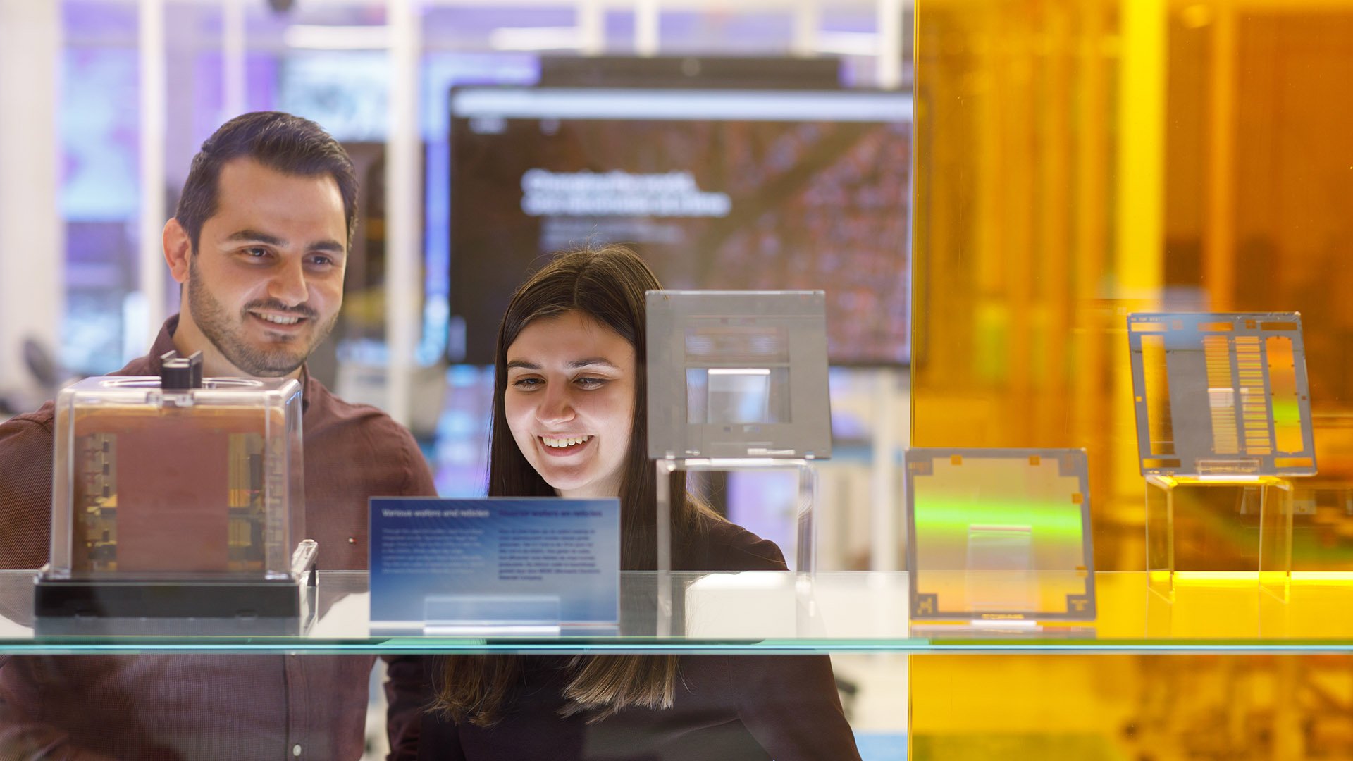 Two people looking at a display of silicon wafers