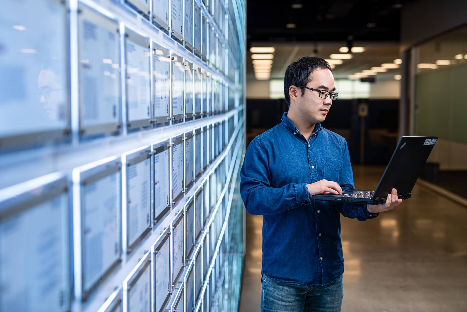 An ASML employee works on his laptop by a wall covered in patents