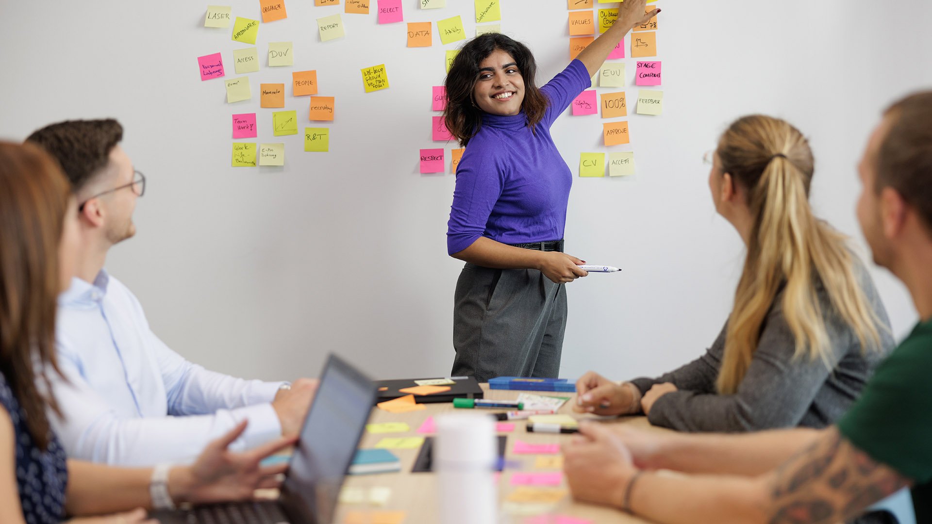 ASML employees are seen having a brainstorming session. A woman is pointing at the sticky notes on a white board. ASML employees are seen having a brainstorming session. A woman is pointing at the sticky notes on a white board.