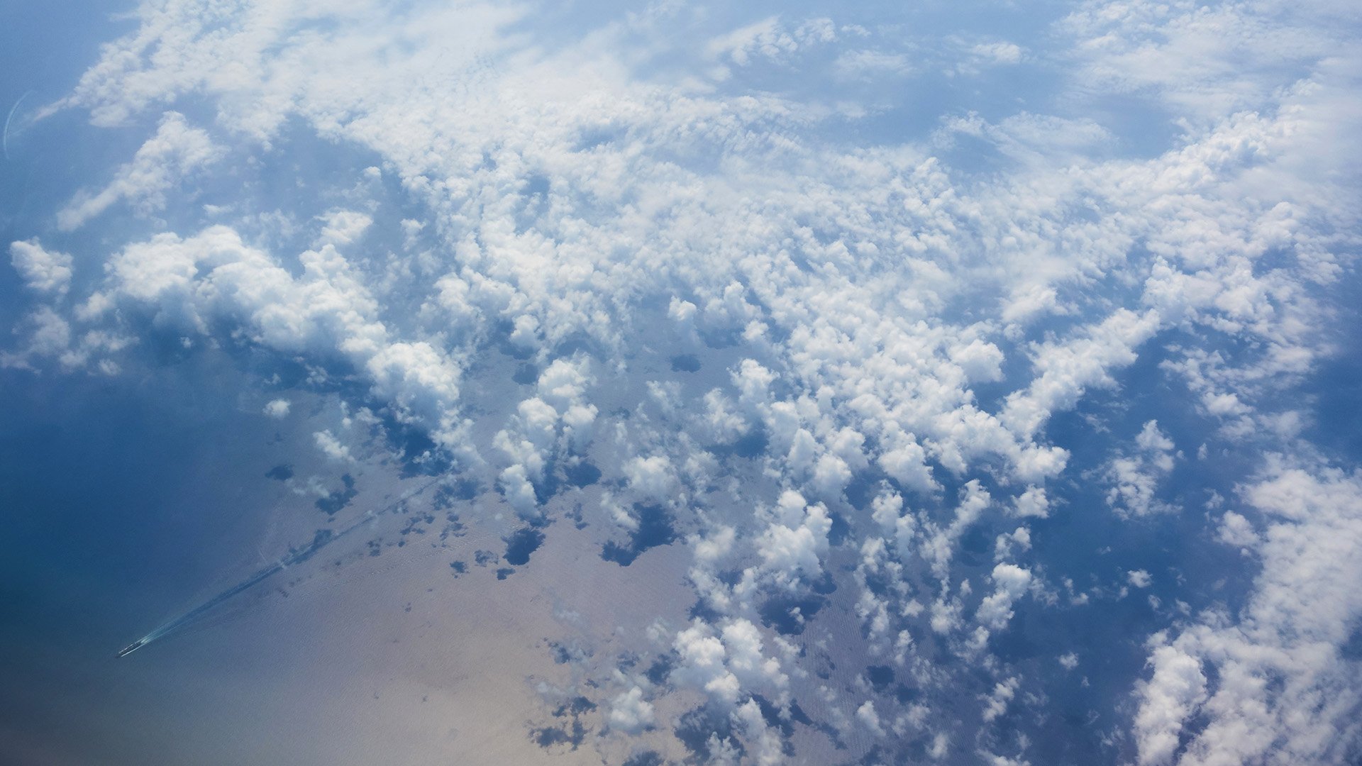 Puffy white clouds casting shadows on the ground